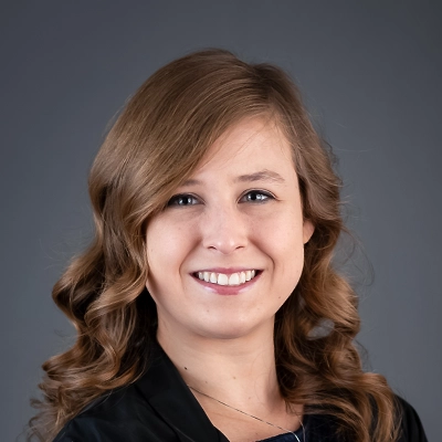 Chiropractor Emily Wilcox Smiling In Front Of Grey Background
